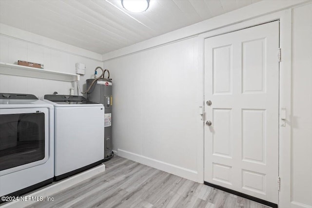 washroom featuring washing machine and dryer, light hardwood / wood-style flooring, and electric water heater