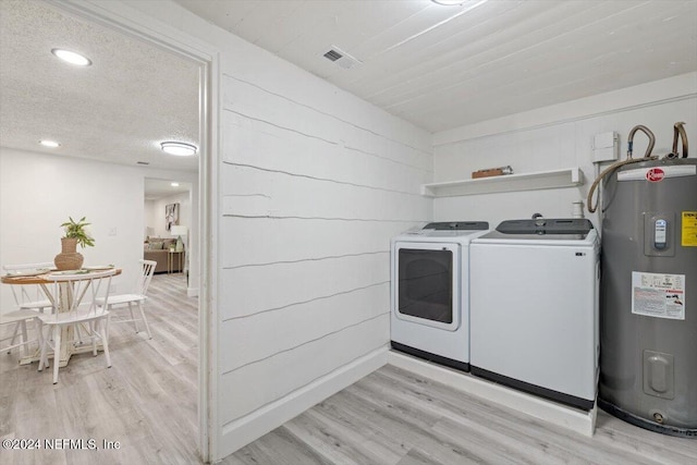 laundry area featuring independent washer and dryer, electric water heater, and light hardwood / wood-style floors