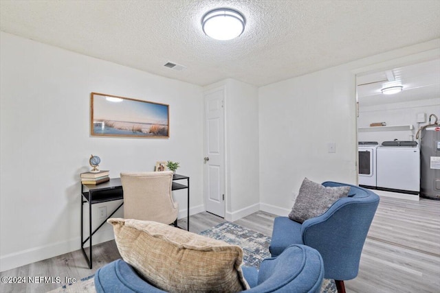 interior space featuring light hardwood / wood-style flooring, a textured ceiling, electric water heater, and separate washer and dryer