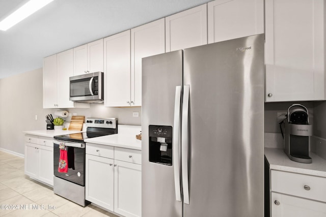 kitchen with appliances with stainless steel finishes, light tile patterned floors, and white cabinets