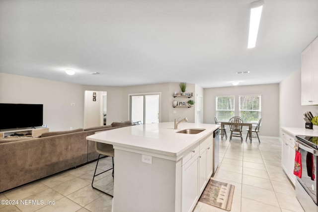 kitchen with white cabinetry, appliances with stainless steel finishes, sink, and a center island with sink