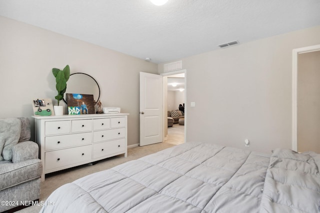 bedroom with a textured ceiling and light colored carpet