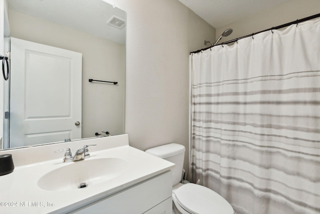 bathroom with vanity, toilet, walk in shower, and a textured ceiling