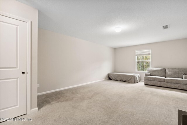 bedroom with a textured ceiling and light colored carpet