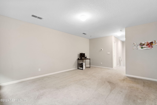 empty room with light carpet and a textured ceiling