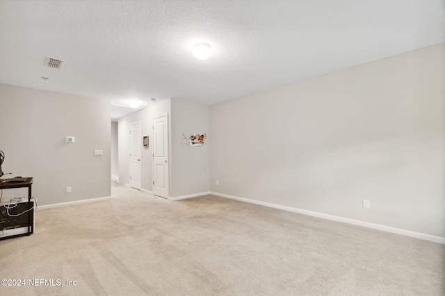 empty room with a textured ceiling and light colored carpet