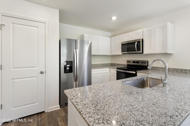 744 Hunter Rd, Hollister, FL 32177 - kitchen featuring appliances with stainless steel finishes, a sink, a peninsula, white cabinets, and light stone counters