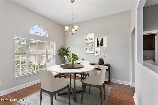 dining area with dark wood-type flooring, an inviting chandelier, and plenty of natural light