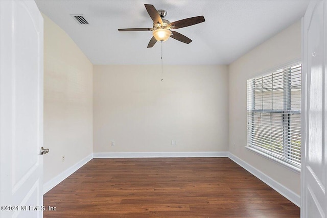 empty room featuring a healthy amount of sunlight, dark wood-type flooring, and ceiling fan