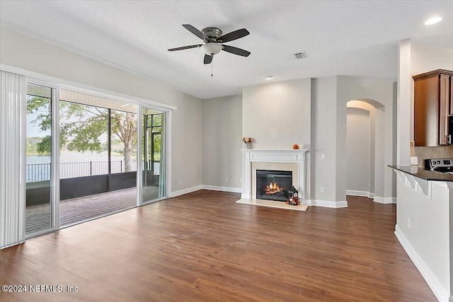 unfurnished living room featuring a textured ceiling, dark wood-type flooring, and ceiling fan