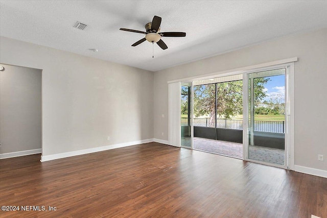 empty room with a textured ceiling, dark hardwood / wood-style floors, and ceiling fan