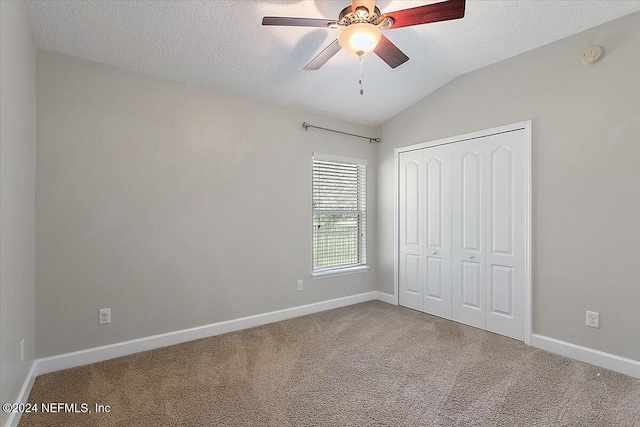 unfurnished bedroom with vaulted ceiling, carpet floors, a closet, and ceiling fan