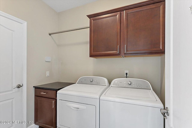 washroom featuring cabinets and washer and clothes dryer