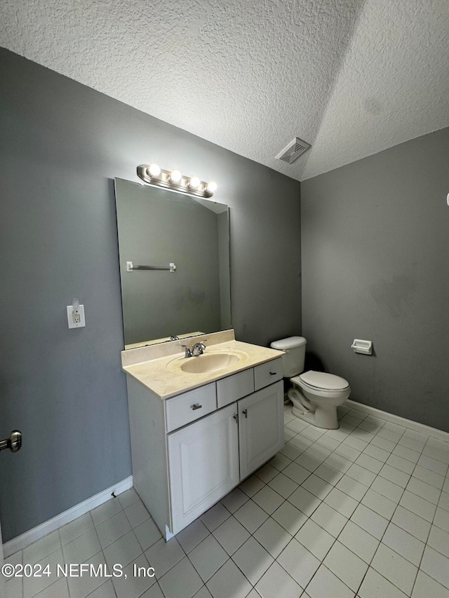 bathroom with toilet, a textured ceiling, vanity, and tile patterned flooring