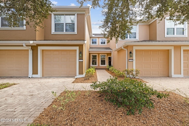 view of property featuring a garage, driveway, and stucco siding