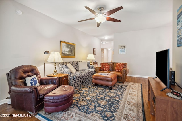 living room with ceiling fan, baseboards, and wood finished floors