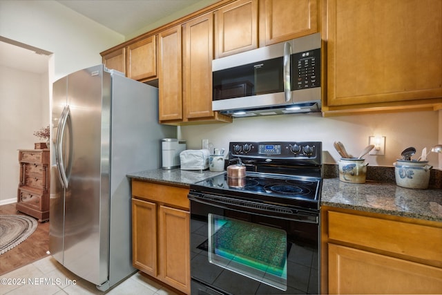 8757 Little Swift Cir Unit 22F, Jacksonville, FL 32256 - kitchen featuring appliances with stainless steel finishes, dark stone counters, brown cabinetry, light tile patterned floors, and arched walkways