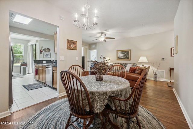 dining space featuring ceiling fan with notable chandelier and light hardwood / wood-style flooring