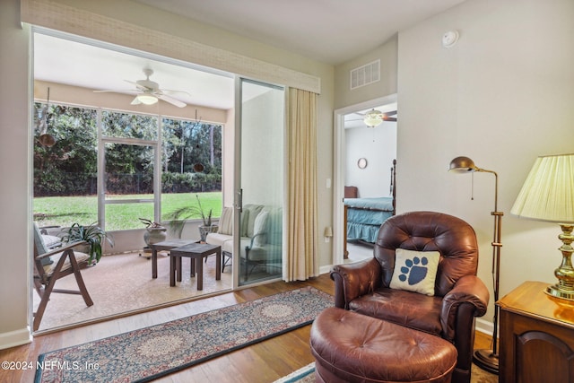 living area with a ceiling fan, baseboards, visible vents, and wood finished floors