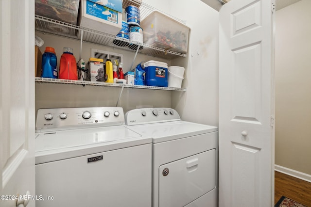 laundry area with laundry area, wood finished floors, washing machine and dryer, and baseboards