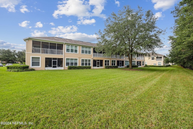 back of property with a yard, a sunroom, and stucco siding