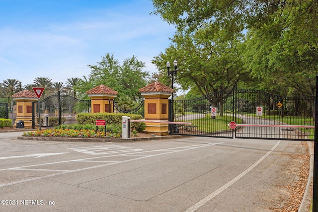 view of street with traffic signs, a gate, a gated entry, and curbs