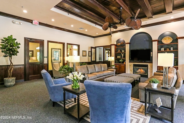 carpeted living area with a wainscoted wall, crown molding, beamed ceiling, and a premium fireplace