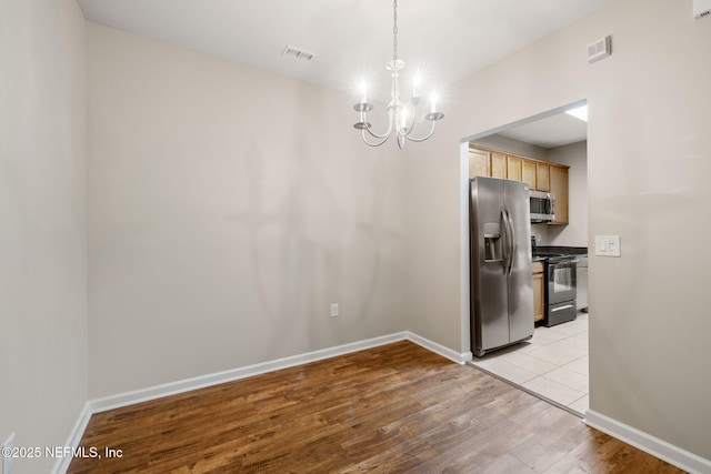 unfurnished dining area with a chandelier, light wood-type flooring, and baseboards