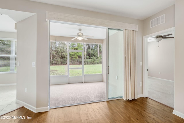 doorway with carpet, baseboards, visible vents, and wood finished floors