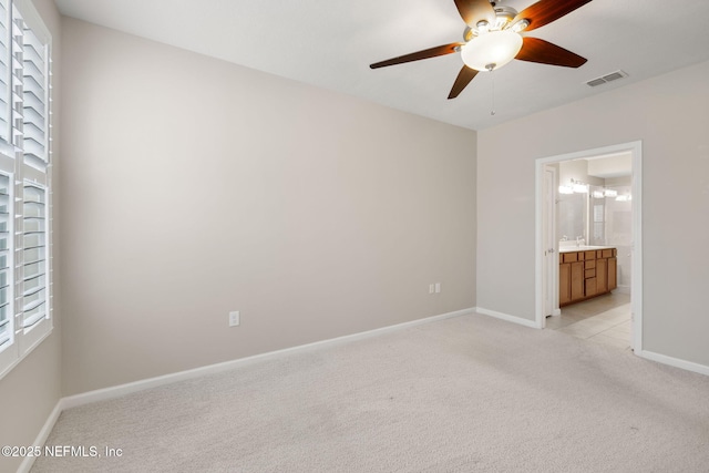 unfurnished bedroom with baseboards, visible vents, light colored carpet, ceiling fan, and ensuite bathroom