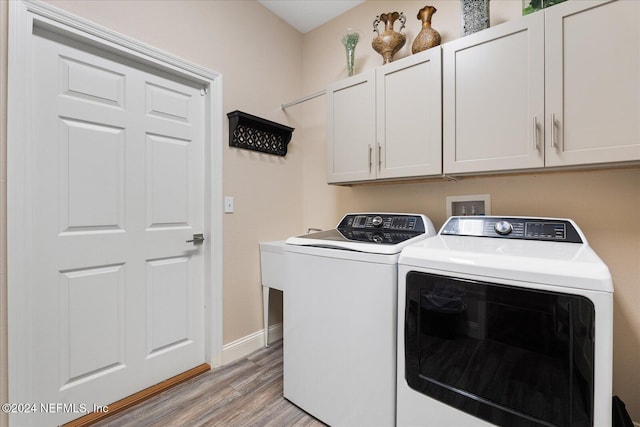 laundry area with washer and clothes dryer, light hardwood / wood-style floors, and cabinets