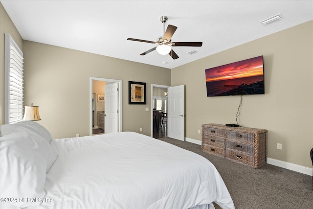 bedroom featuring connected bathroom, dark colored carpet, and ceiling fan