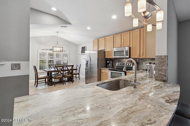 kitchen featuring stainless steel appliances, sink, hanging light fixtures, a chandelier, and vaulted ceiling