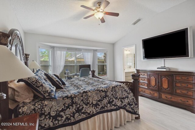 bedroom featuring ensuite bathroom, ceiling fan, a textured ceiling, lofted ceiling, and light wood-type flooring