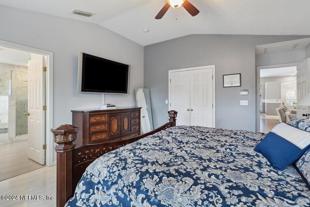 bedroom featuring connected bathroom, light wood-type flooring, lofted ceiling, and ceiling fan