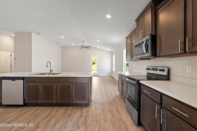 kitchen with light wood finished floors, lofted ceiling, appliances with stainless steel finishes, light countertops, and a sink