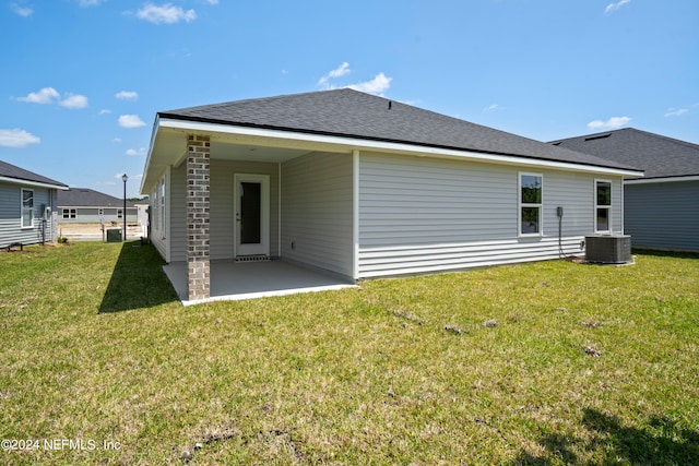 rear view of house with a shingled roof, a patio area, and a yard