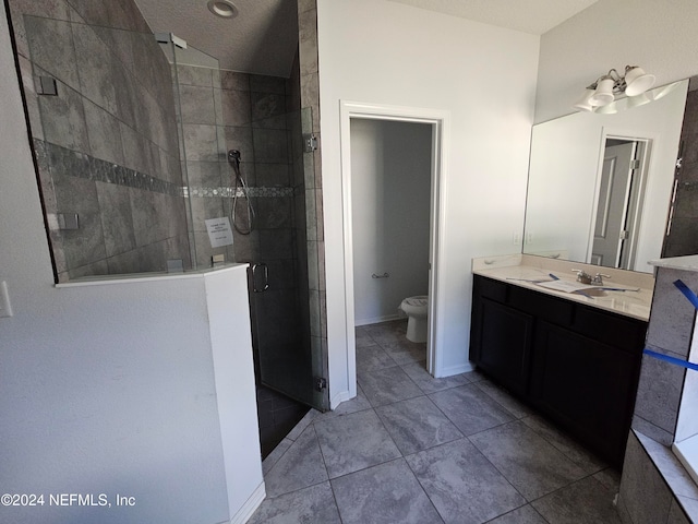 bathroom with tile patterned floors, toilet, vanity, a textured ceiling, and walk in shower