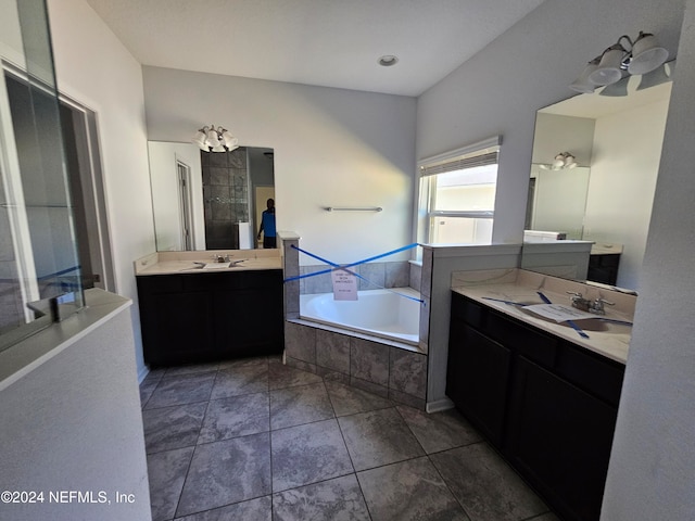 bathroom featuring vanity, tile patterned flooring, and tiled bath