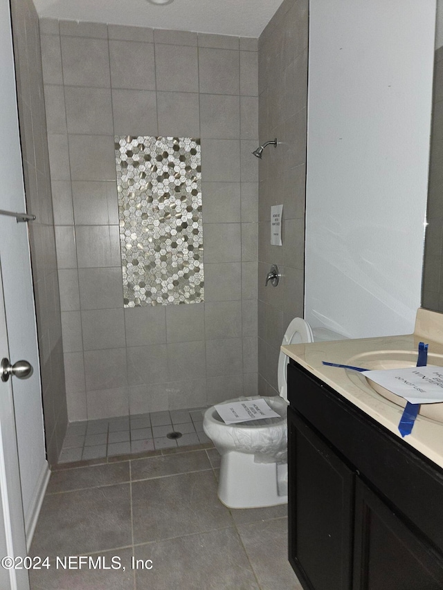 bathroom featuring vanity, toilet, tiled shower, and tile patterned flooring