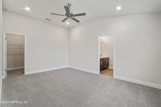 unfurnished bedroom featuring lofted ceiling, connected bathroom, a closet, a spacious closet, and ceiling fan