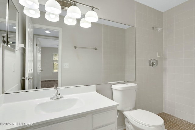 bathroom with vanity, tiled shower, and toilet