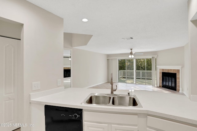 kitchen featuring sink, white cabinetry, dishwasher, a tile fireplace, and ceiling fan