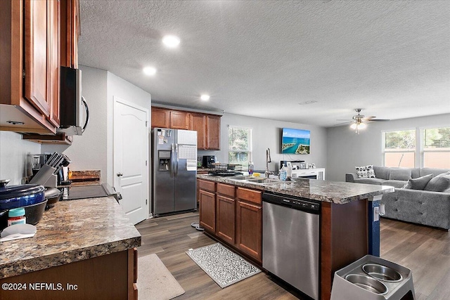 kitchen with stainless steel appliances, a center island with sink, plenty of natural light, and dark hardwood / wood-style flooring