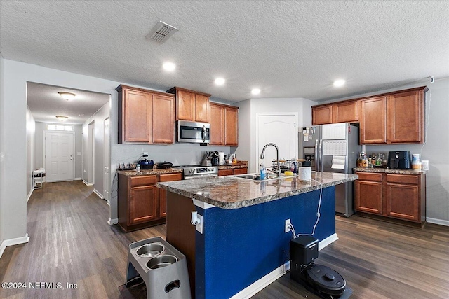 kitchen with a center island with sink, a textured ceiling, stainless steel appliances, and dark hardwood / wood-style floors