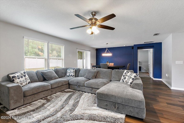 living room with ceiling fan, a textured ceiling, and dark hardwood / wood-style flooring