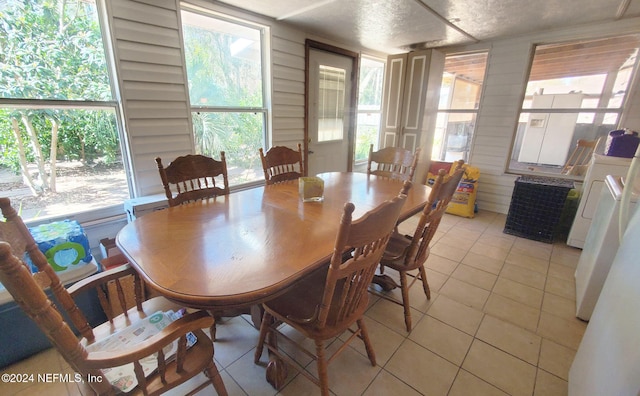 dining area featuring washer / dryer, a textured ceiling, light tile patterned flooring, and plenty of natural light