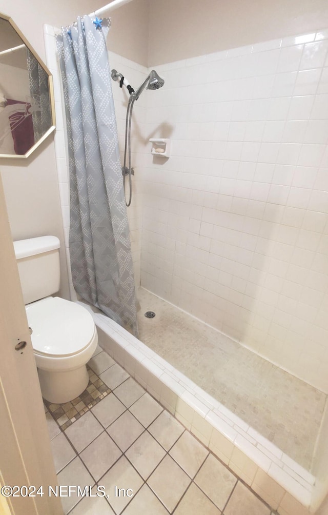 bathroom featuring toilet, a shower with curtain, and tile patterned flooring