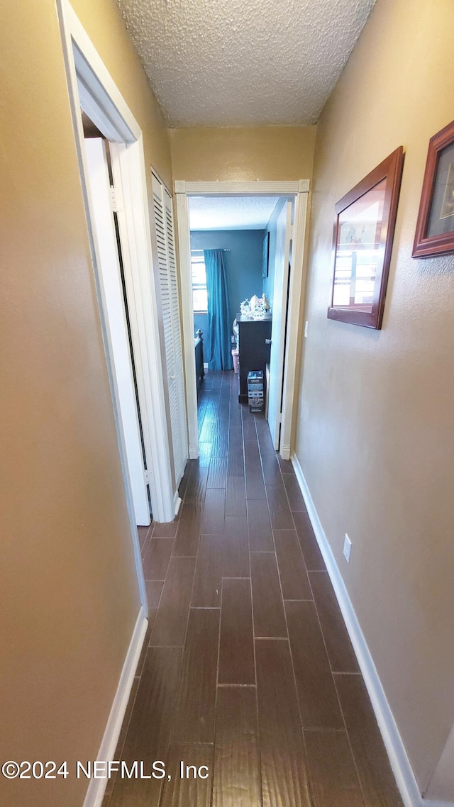 corridor with dark wood-type flooring and a textured ceiling