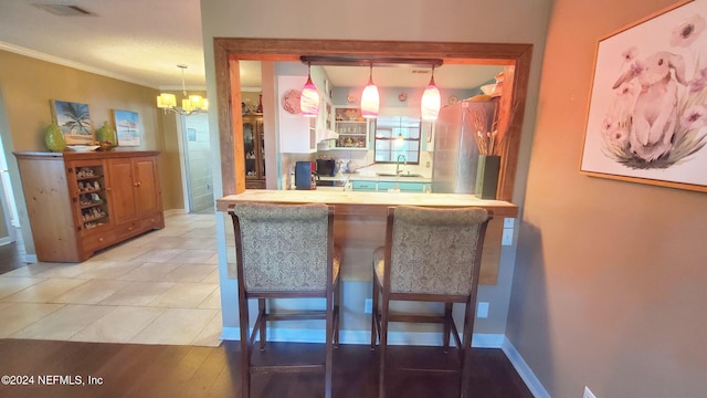 kitchen featuring sink, a breakfast bar, decorative light fixtures, and wood-type flooring